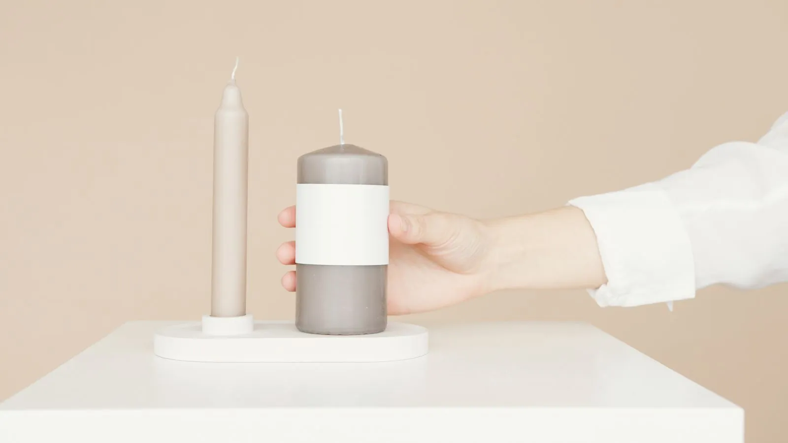 A hand holding a candle with a blank label, perfect for product mockup and branding.